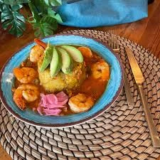 Shrimp mofongo topped with avocado on a turquoise plate