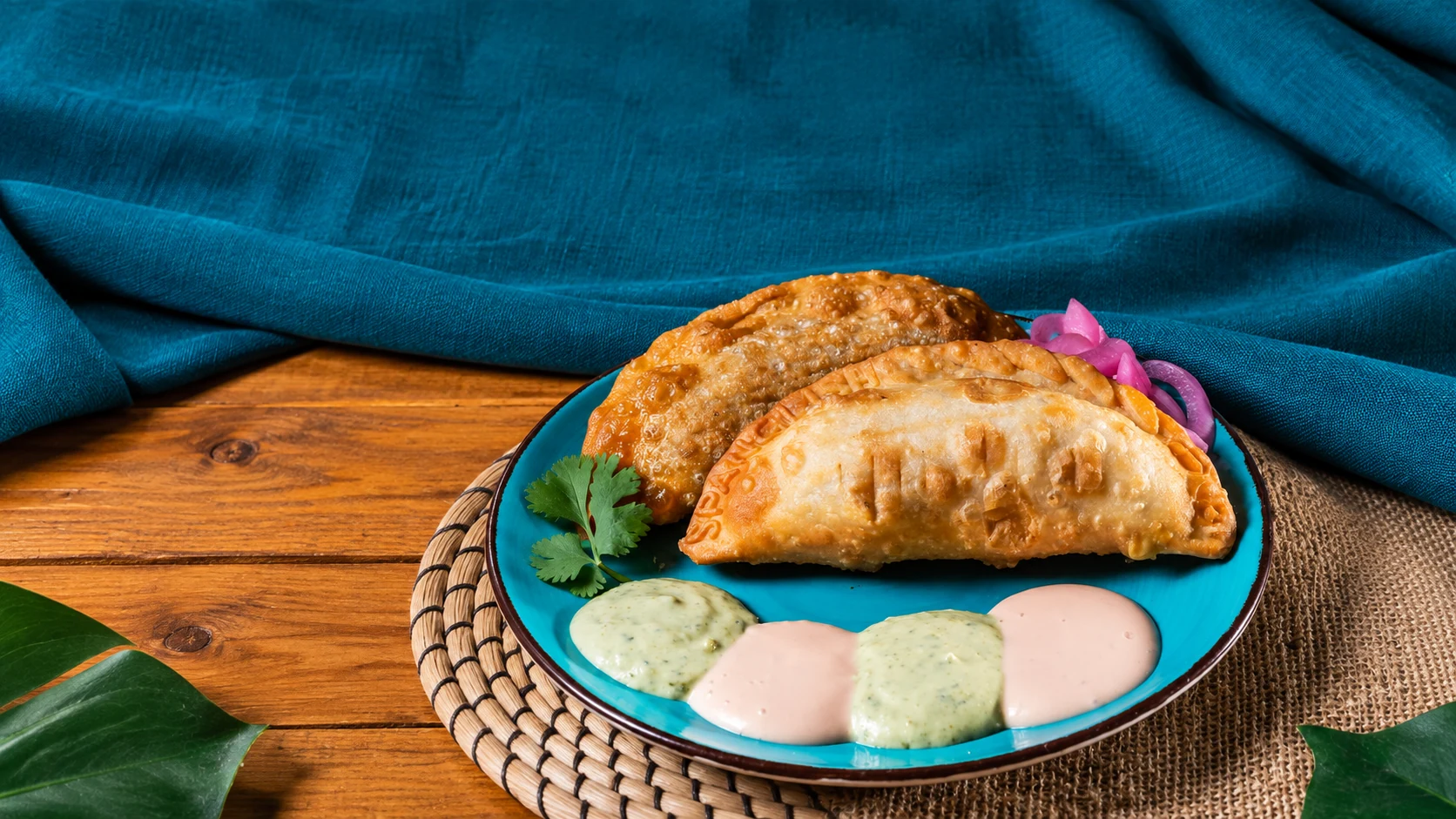 Kokí empanadas and house sauces on a turquoise plate