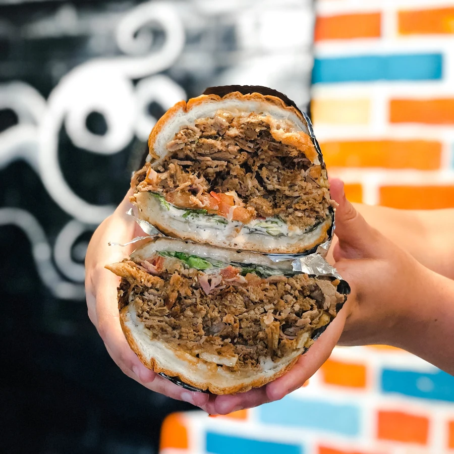 Kokí tripleta sandwich cut in half, showing the meat filling on sobao bread
